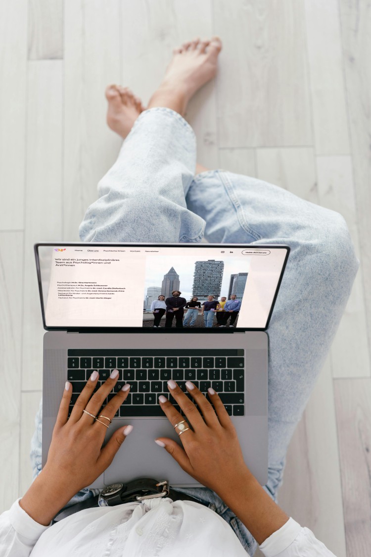Junge Frau sitzt mit einem Laptop auf dem Schoß und ruft die Website von ancora auf.