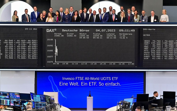 Team beim Börsenstart des Invesco FTSE All-World ETF auf dem Parkett der Frankfurter Börse unter der DAX-Anzeigetafel.